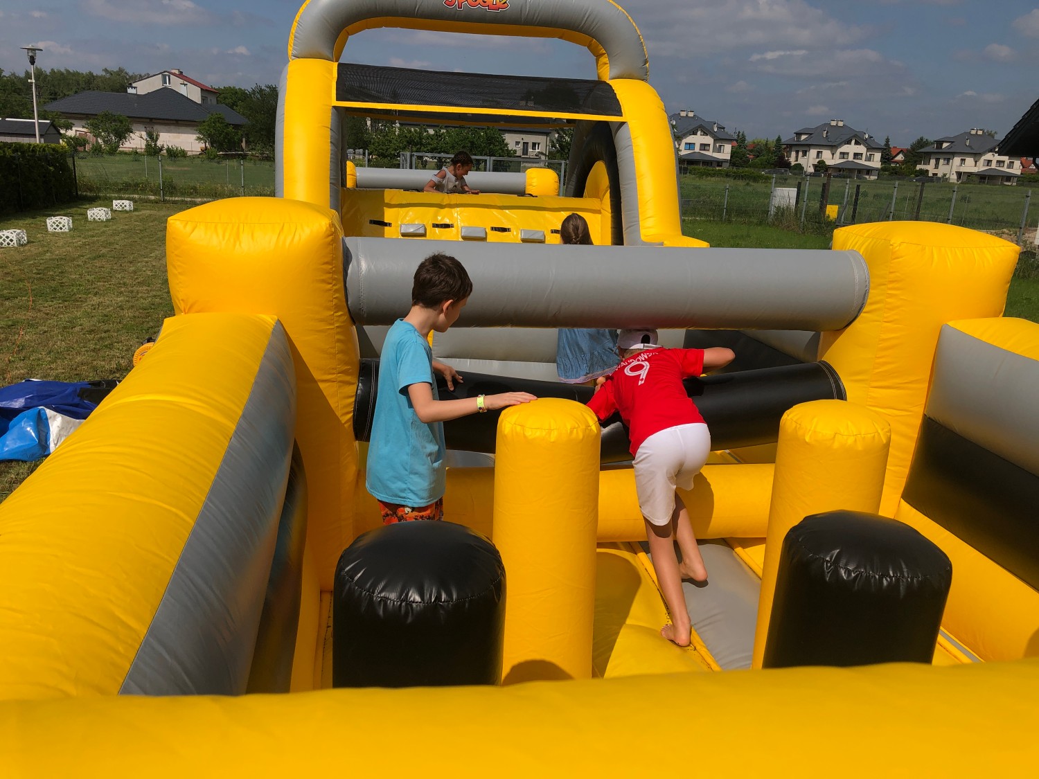 Dzieciaki korzystają z dmuchanego toru przeszkód na imprezie urodzinowej w Warszawie