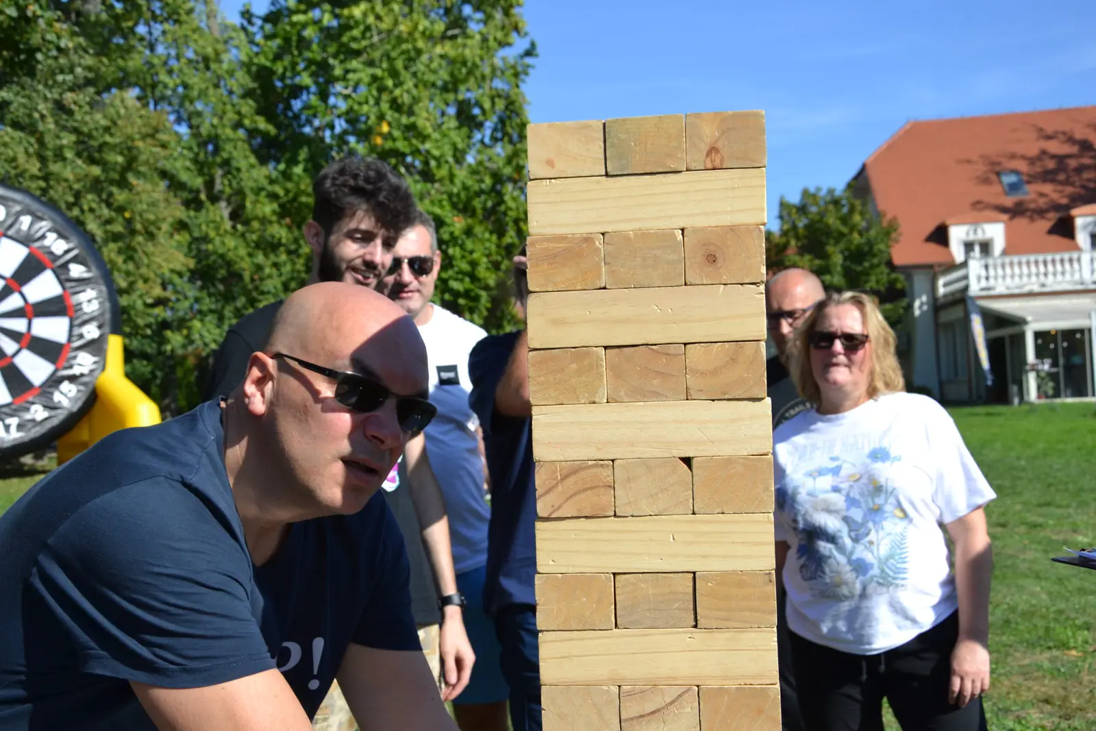 Gracze w skupieniu obserwują wysoką wieżę Giga Jenga podczas pikniku